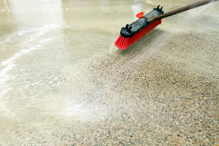 Cleaning a patio with a brush and soapy water. Getty Images