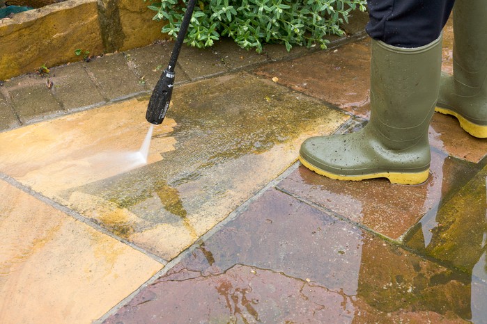 Using a pressure washer to clean a patio. Getty Images