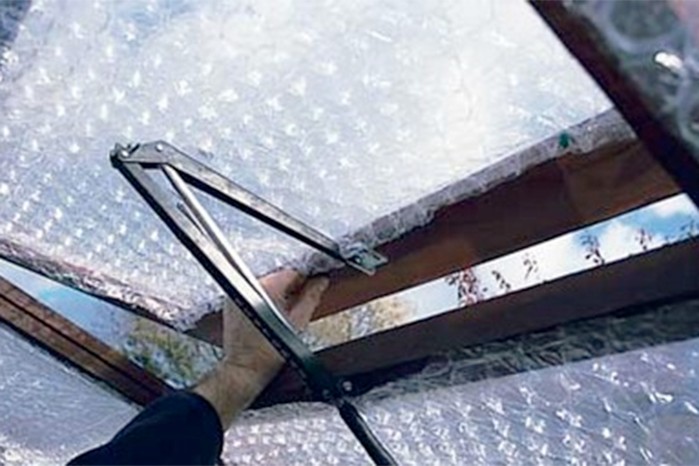 Fitting panels of bubble-wrap into panes of a greenhouse